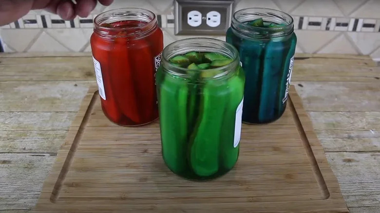 three jars of Mountain-Dew-infused pickles in red, green, and blue