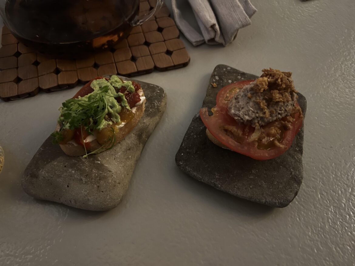 Bruschettas on rocks they probably brought from the beach across the road. Are the crumbs supposed to just scatter across the table?