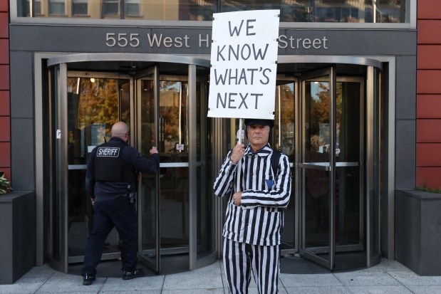 Protester, including Lee Goodman, in stripes, stands outside of the Domestic Violence Courthouse in Chicago,  Sept. 4, 2025. (Antonio Perez/Chicago Tribune)