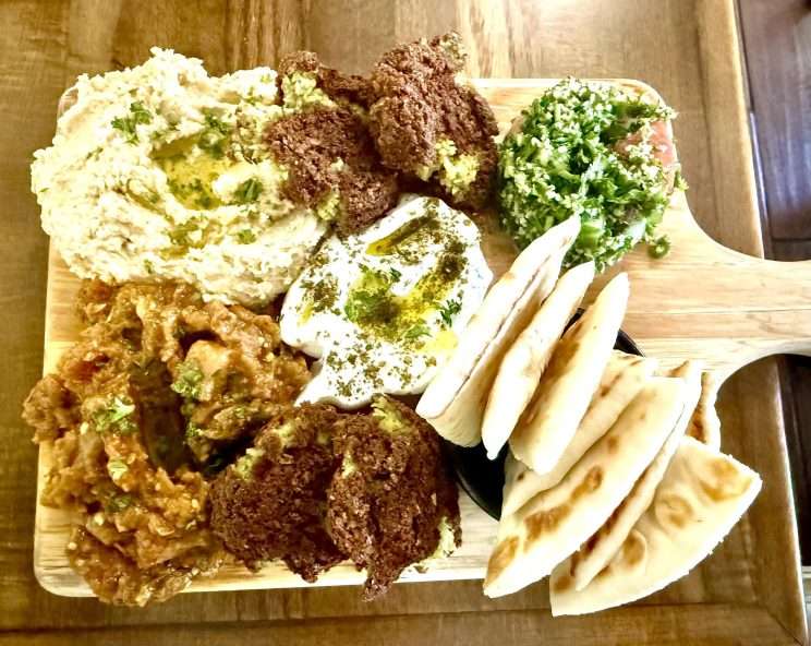 a vegetarian sampler with falafel, hummus, labneh, Moroccan ratatouille, and tabbouleh served with za'atar pita bread.