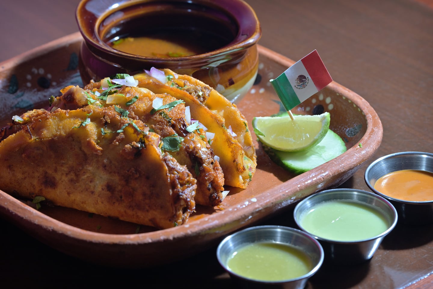 Pátzcuaro's birria tacos, filled with braised beef, cheese, onion, and cilantro, served with beef consomme. House-made salsas elevate whatever they touch.