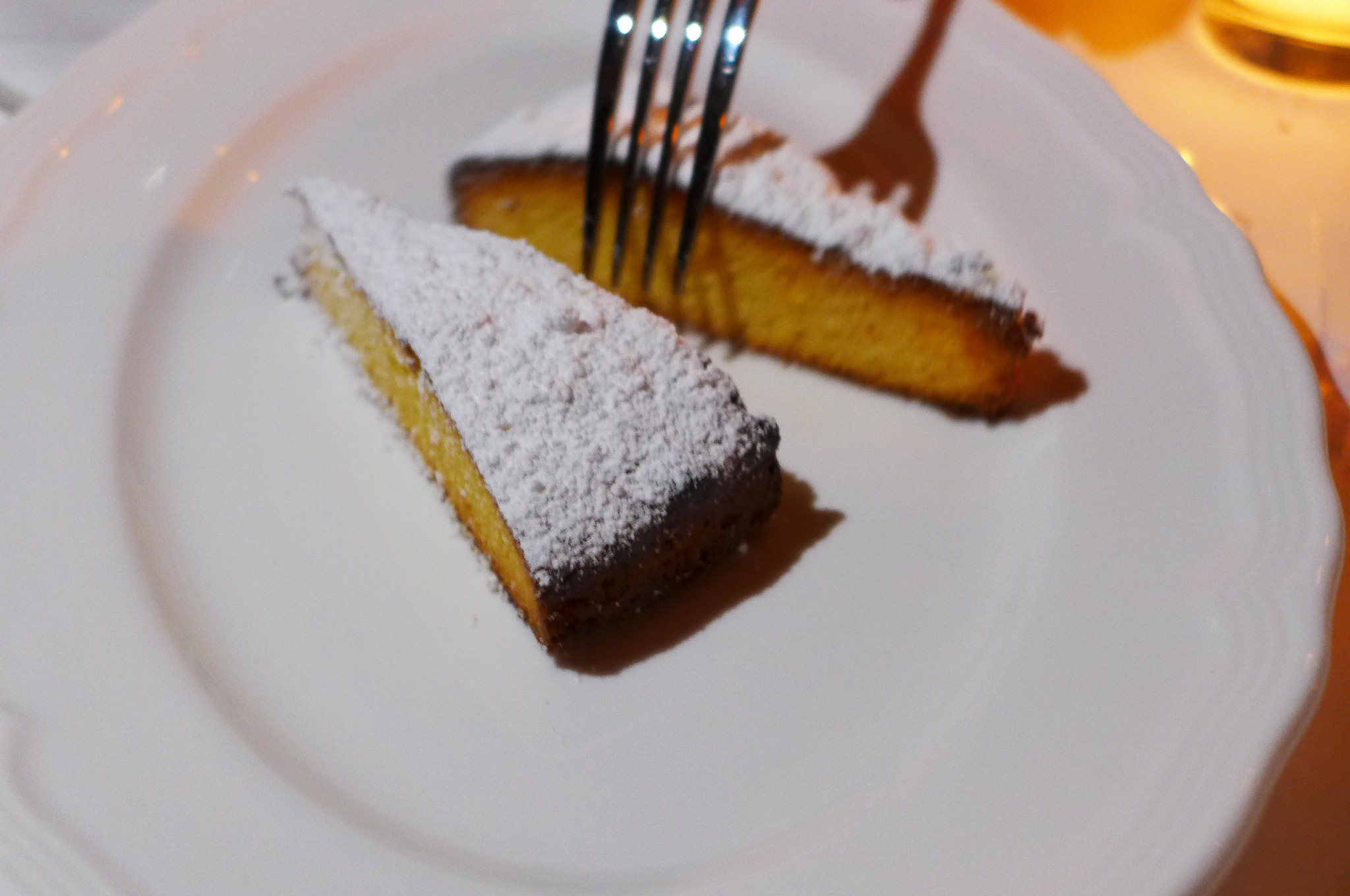 Two yellow wedges of cake topped with white powdered sugar.