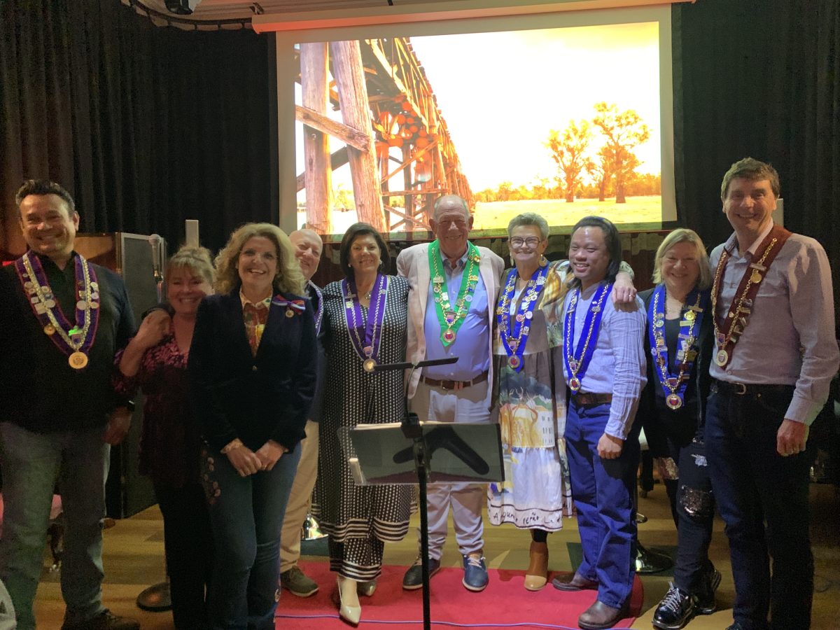 A group photo of eight people wearing ribbons and medallions. 