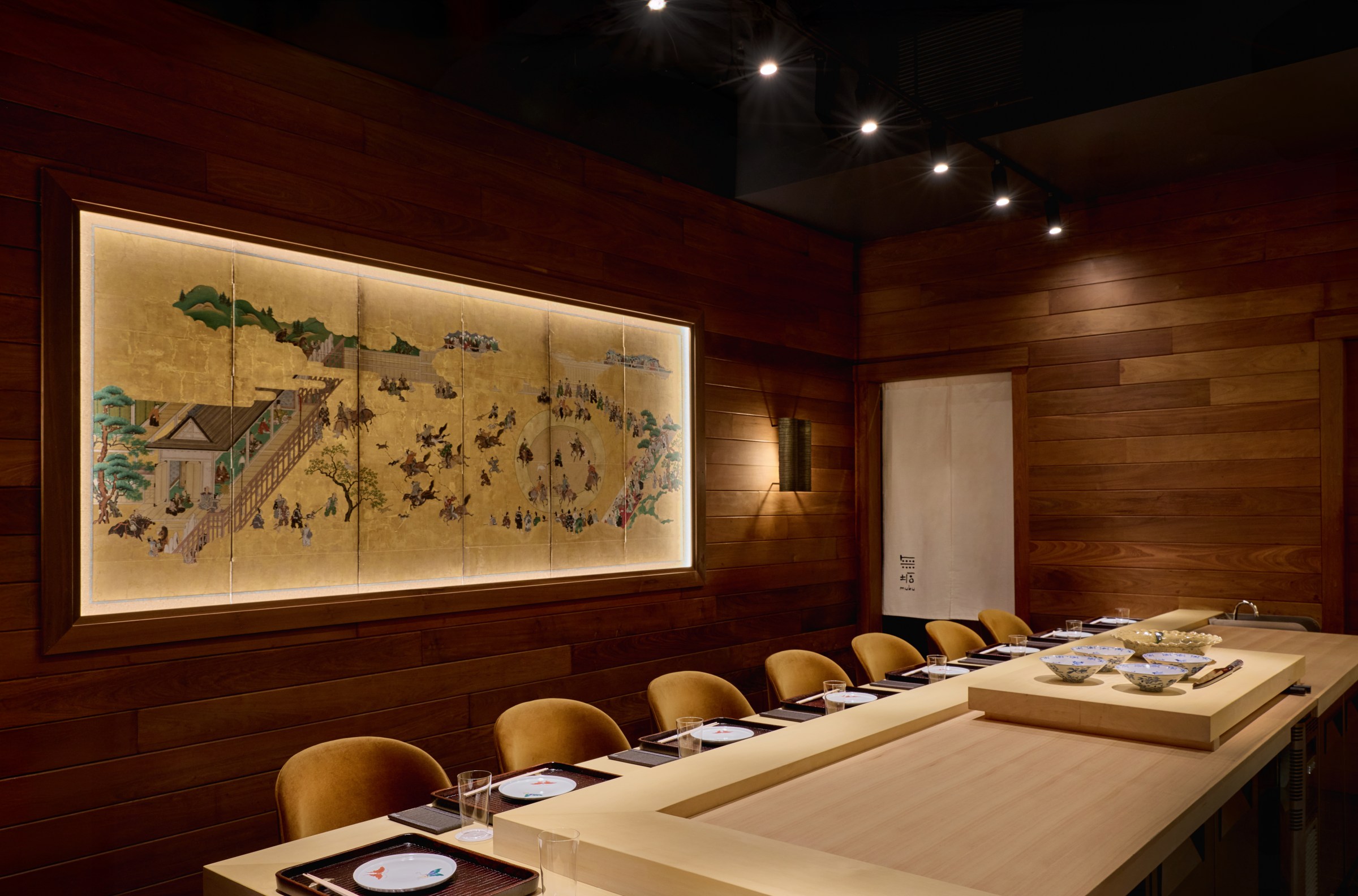 A restaurant dining room with counter seats and artwork on the wall behind it.