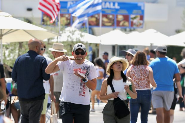 An attendee feasts on souvlaki as he strolls through the...