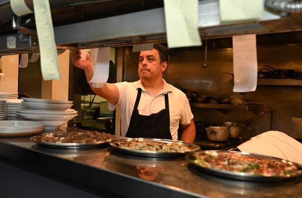 Chef De Cuisine Eric Samaniego checks a ticket as at...