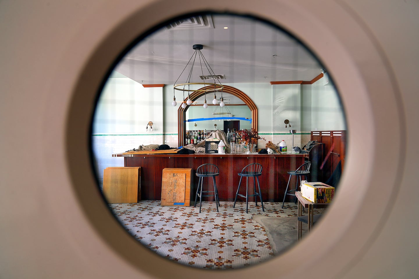 A view through a porthole window of the dining room bar area while it was under renovation in the summer of 2025.
