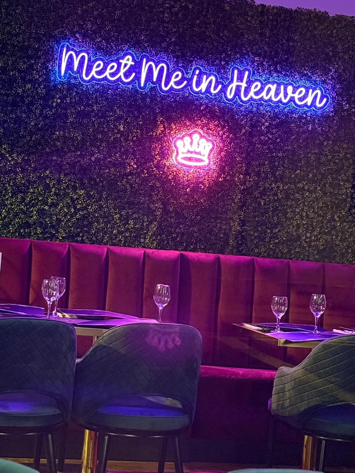 Neon sign reading “Meet Me in Heaven” with velvet seating inside Heaven Restaurant in Stone.