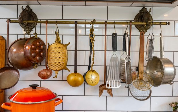 A variety of cooking utensils hangs on a rack in...