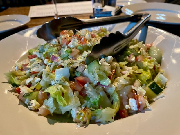 A salad with lettuce, cucumber, feta, pepperoni and Italian dressing