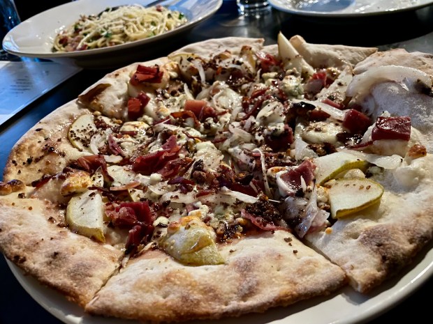 A pizza topped with prosciutto, pears and gorgonzola