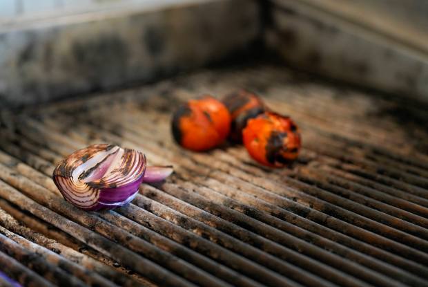 Grilling onions and tomatoes for the cochinita marinade. (Alejandro Tamayo...