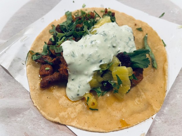 The Taco Stand's al pastor taco has slices of pineapple, cilantro and creamy guacamole salsa on a handmade corn tortilla.(Carlos Rico / The San Diego Union-Tribune)