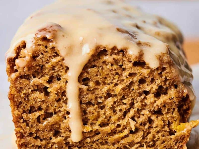 A close-up of a sliced loaf of bread with a light brown glaze drizzled over the top.