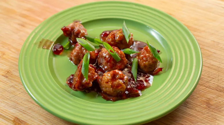 plate of grape jelly meatballs garnished with green onion