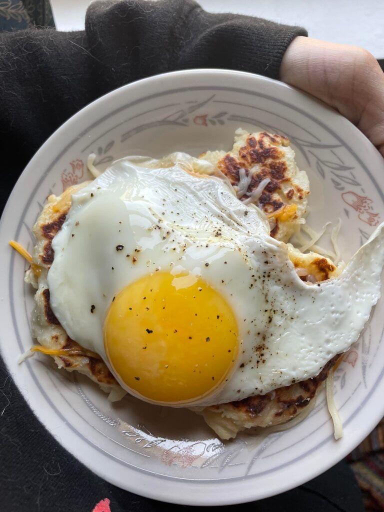 leftover mashed potato pancakes topped with shredded cheese and a sunny side up egg <3