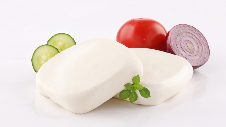 Two blocks of akawi cheese with some vegetables as garnish