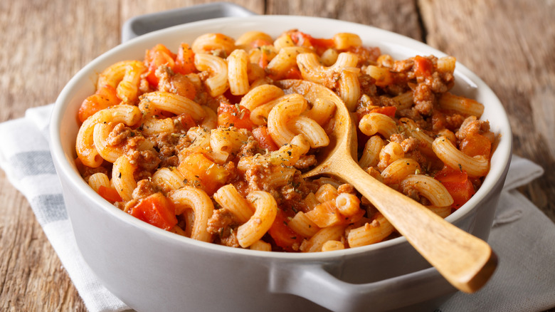 white ceramic bowl of American goulash with a wooden spoon