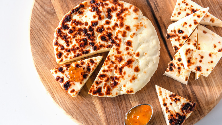 A wheel of Finnish bread cheese cut into wedges with jam