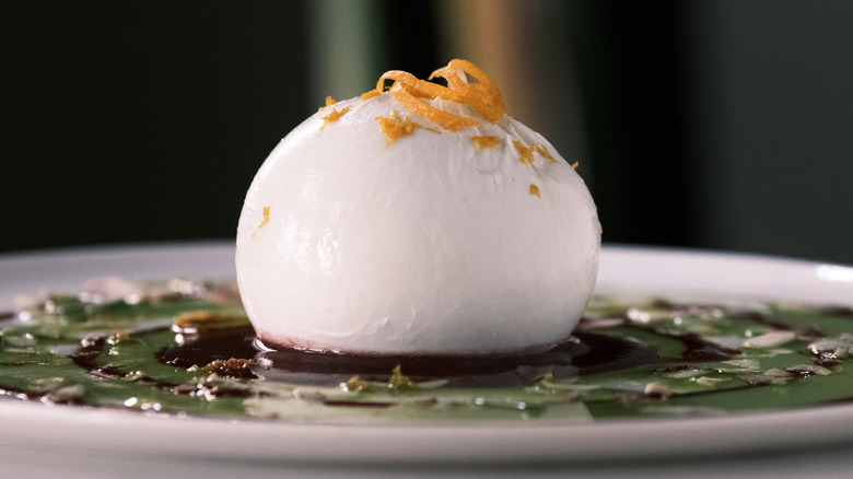 close up burrata cheese with orange zest on plate