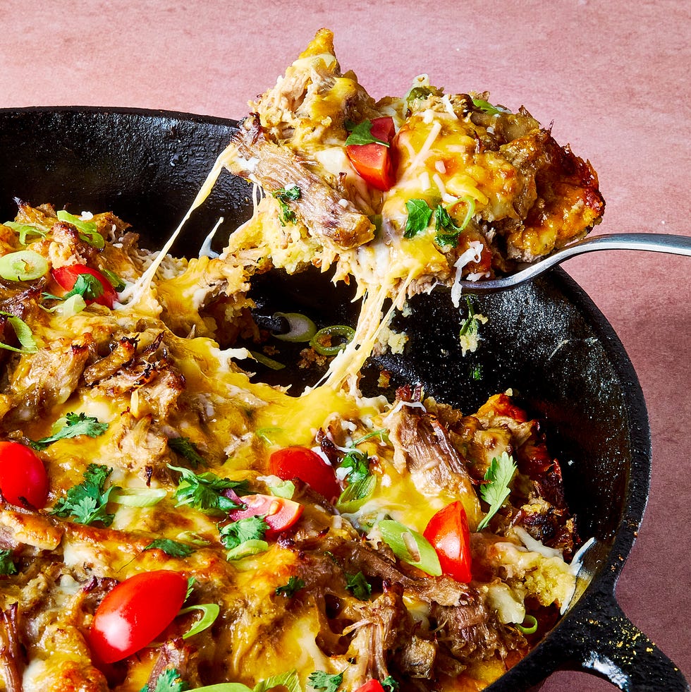 carnitas tamale pie topped with sliced cherry tomatoes, sliced scallions, and chopped cilantro