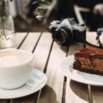 coffee, chocolate cake, camera, flowers on table