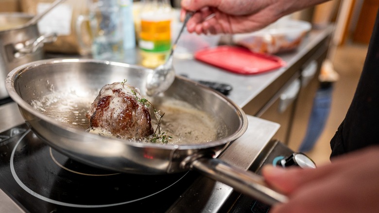 Chef butter-basting steak in hot pan