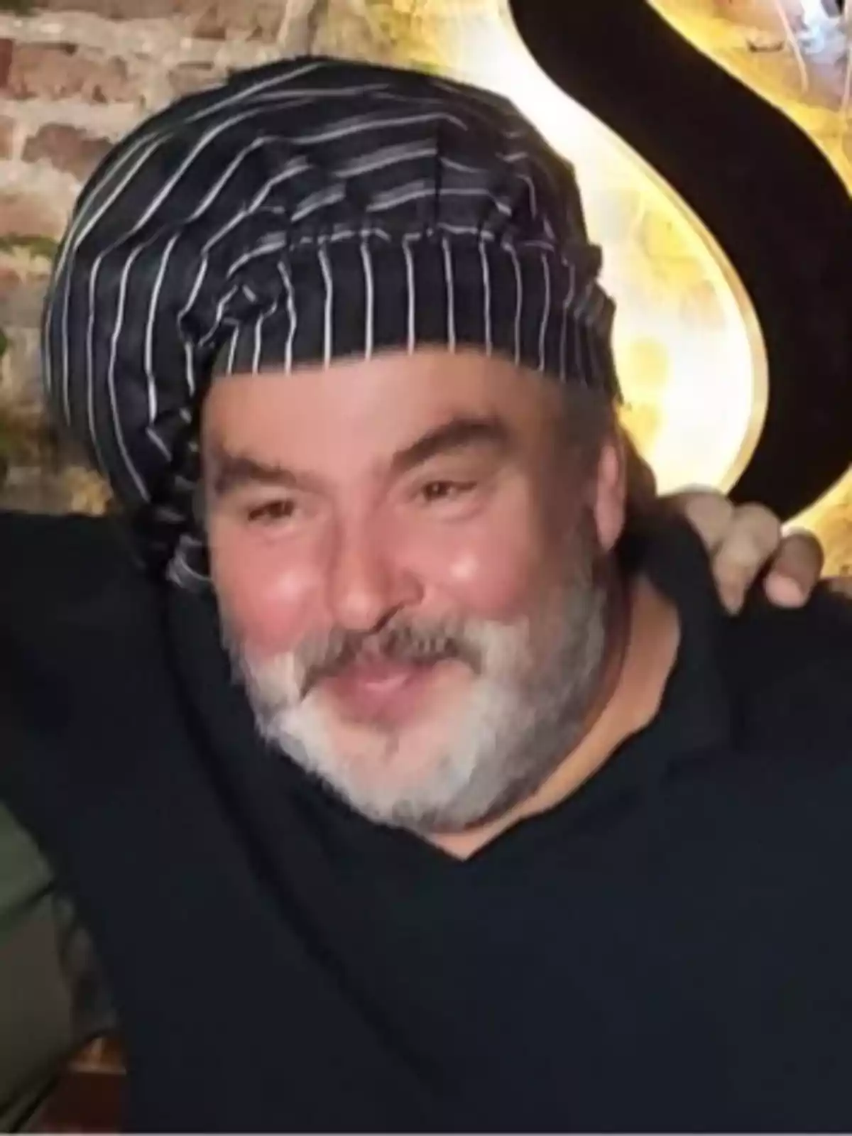 Dámaso Vergara smiling with a beard and a striped chef's hat in an indoor setting