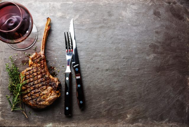 Grilled beef barbecue Veal rib Steak on bone and Argentinean wine on stone slate background
