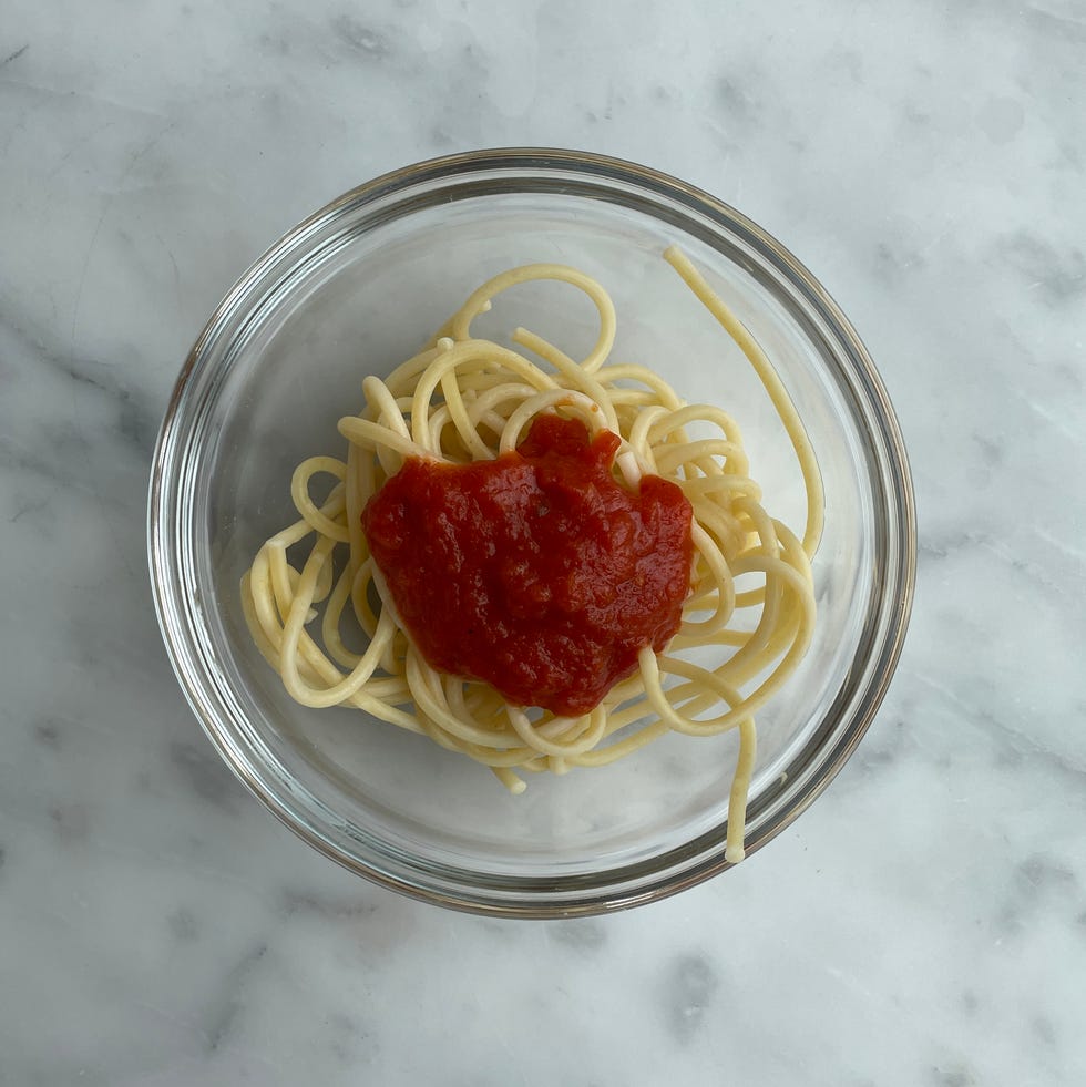 A serving of spaghetti topped with tomato sauce in a glass bowl a serving of spaghetti topped with tomato sauce in a glass bowl