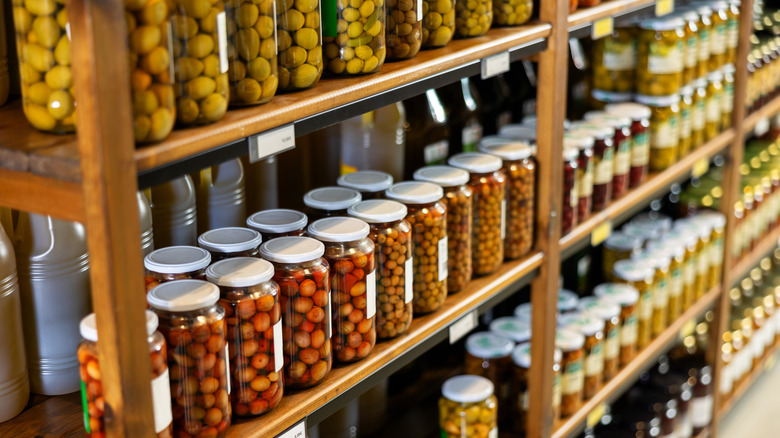 jars of olives at store on a wooden shelf at the grocery store
