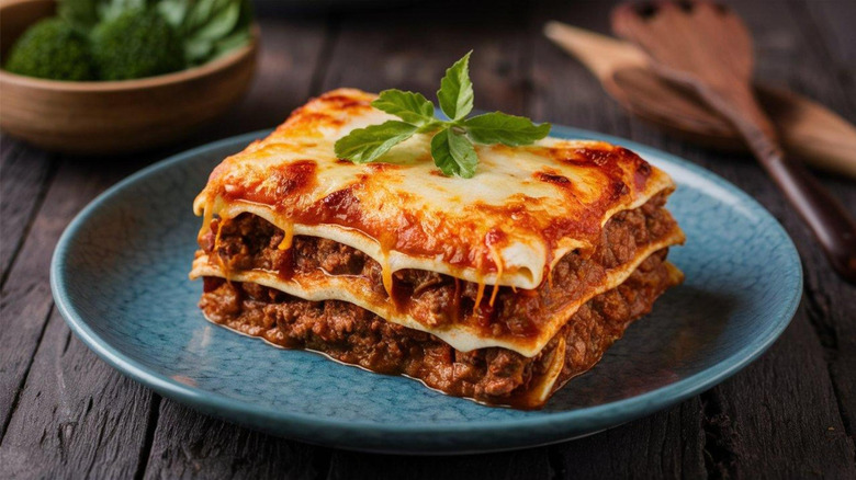 Slice of lasagne served on a blue plate.