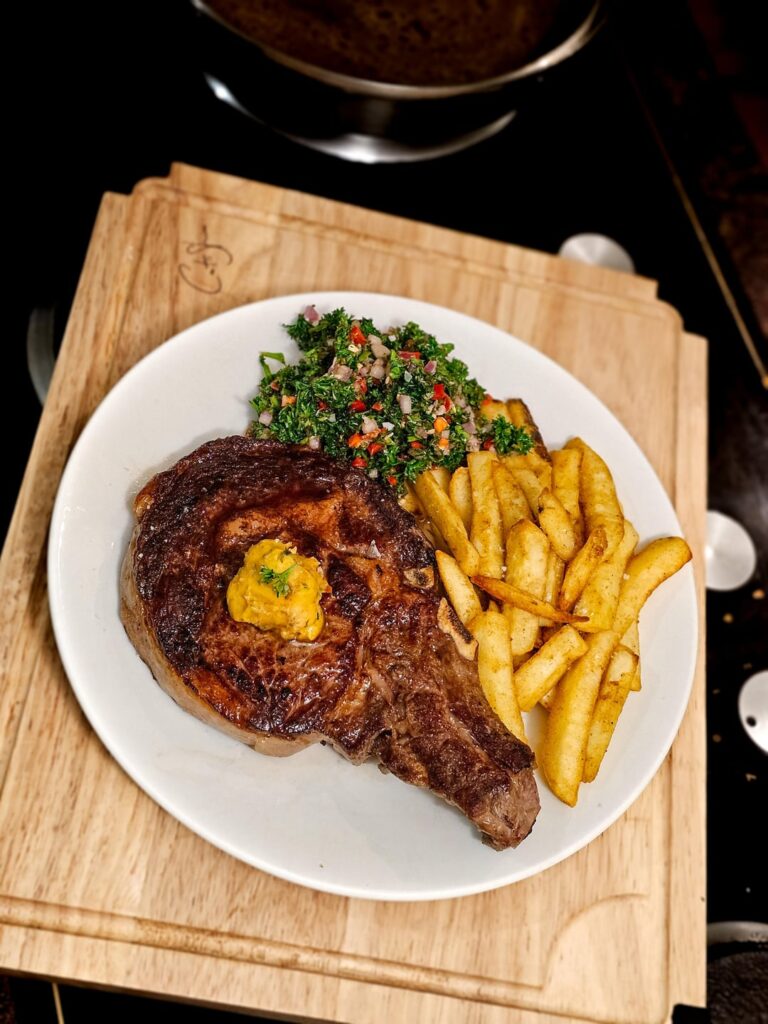 [Homemade] Bone-in ribeye with Café de Paris butter, chimichurri 'salad', and chips.