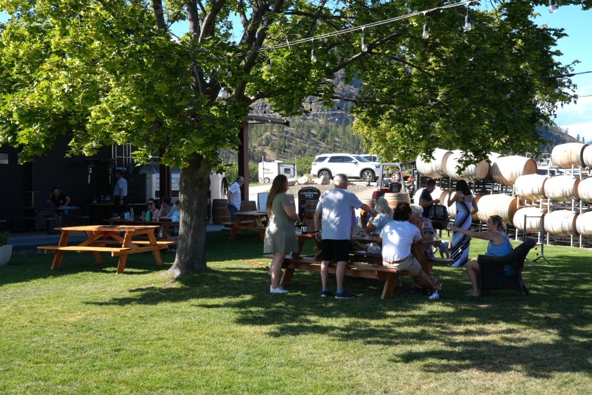 People sit at a an outdoor table at a the Lightning Rock winery in Summerland.