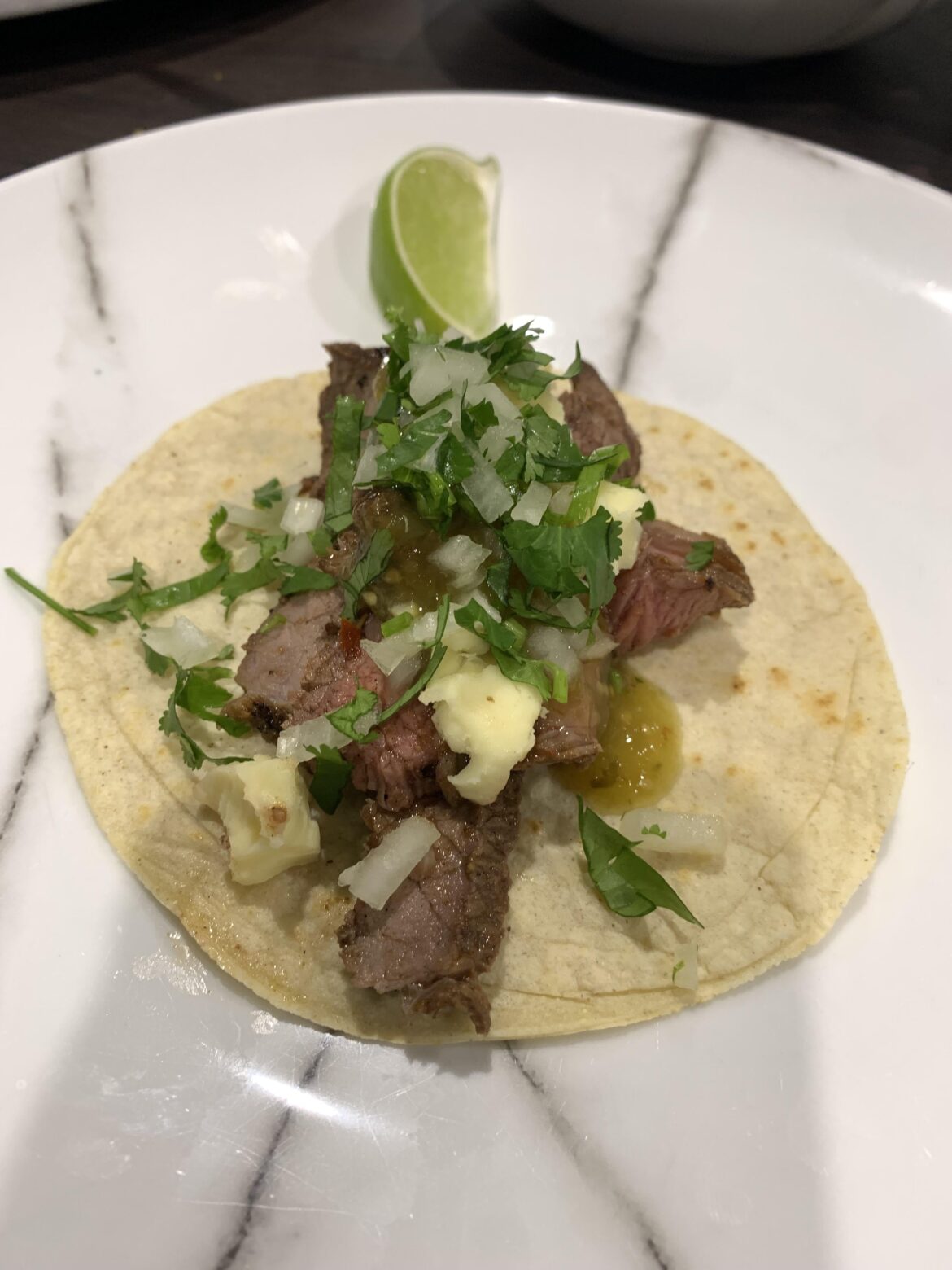 Carne asada on homemade corn tortillas with queso fresca, salsa verde, onion and coriander