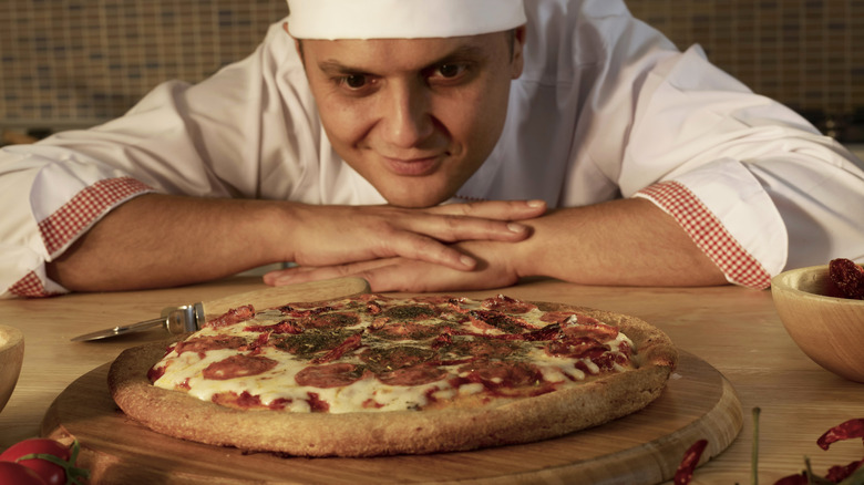 Male chef looking at pizza