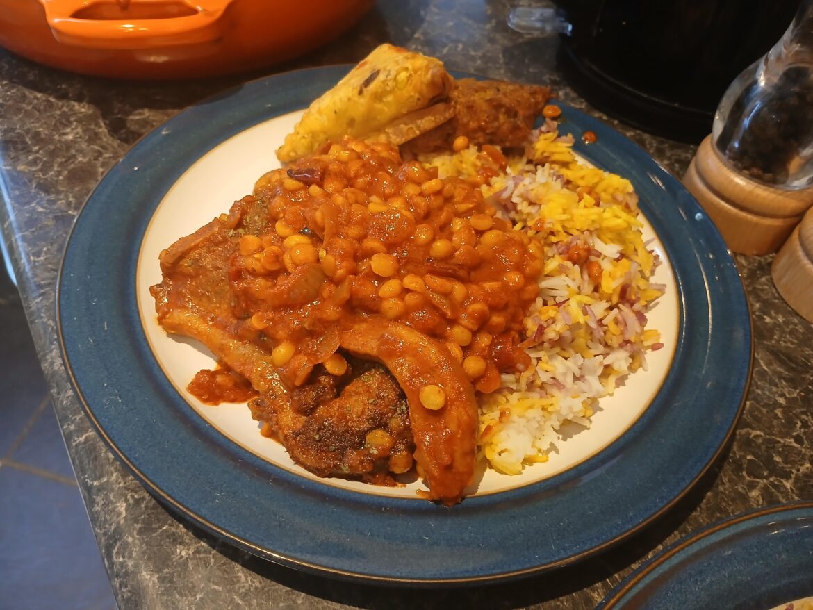 Tandoori lamb chop and lentil curry with coloured rice, a samosa and a bhaji