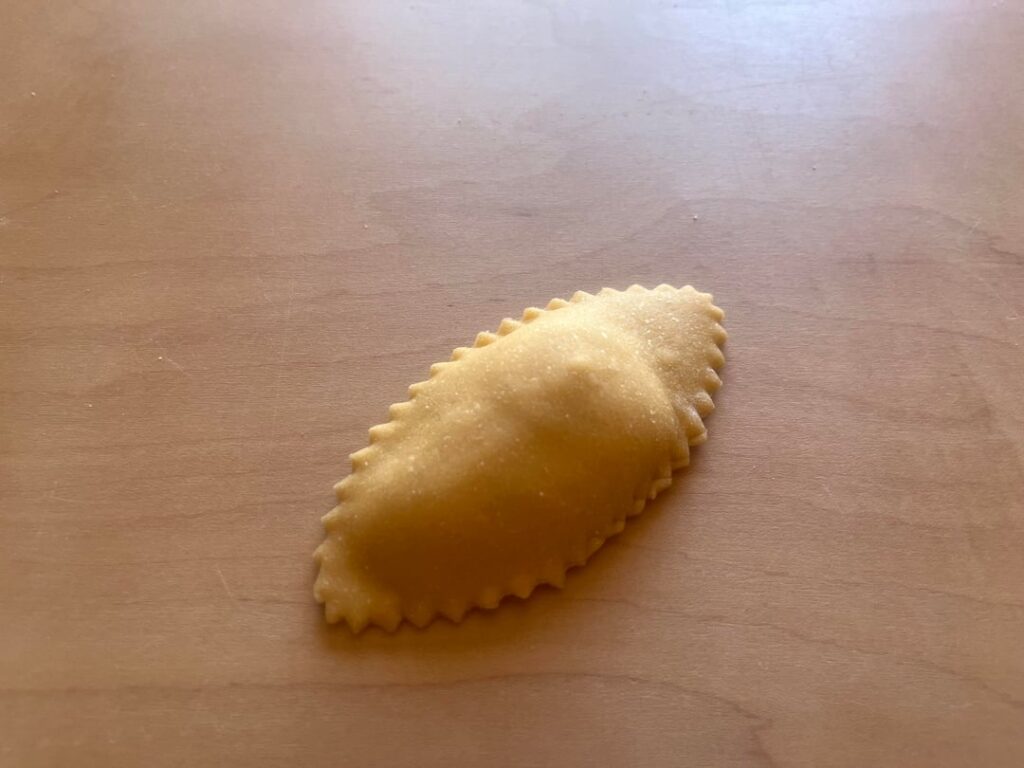 Oval ravioli with brown butter sauce, pecorino, and toasted pine nuts