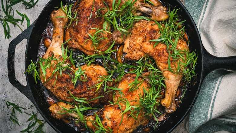 Chicken cooked in cast iron skillet with tarragon on top.