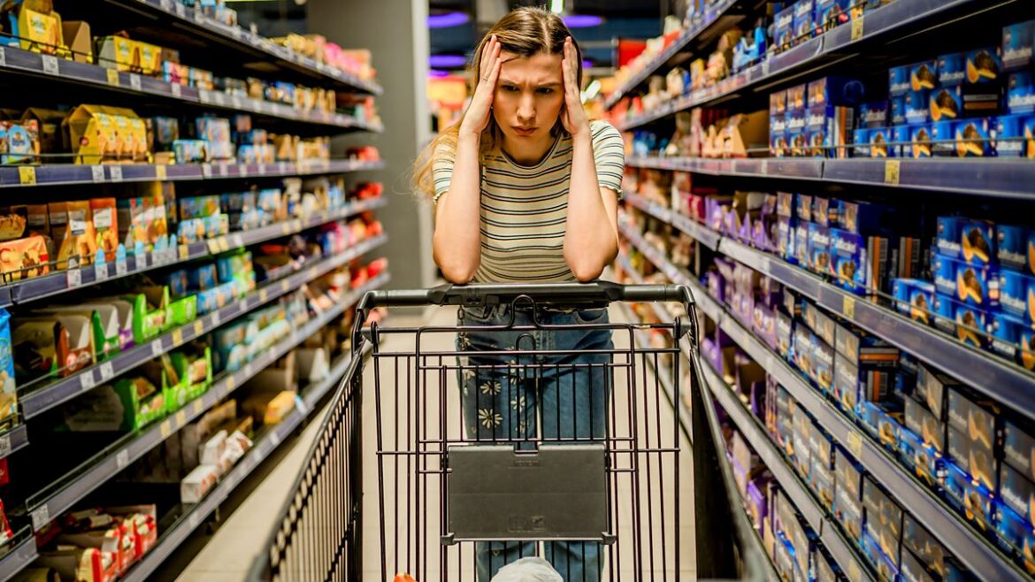 Woman standing in the supermarket looking stressed while surrounded by snacks