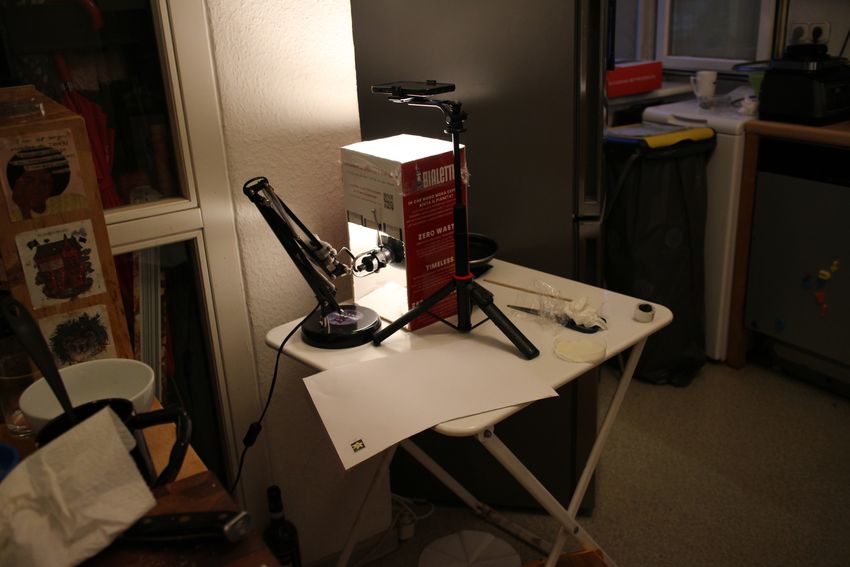 A lightbox made out of a stand and cardboard boxes sits on a table. A lightbox made out of a stand and cardboard boxes sits on a table.