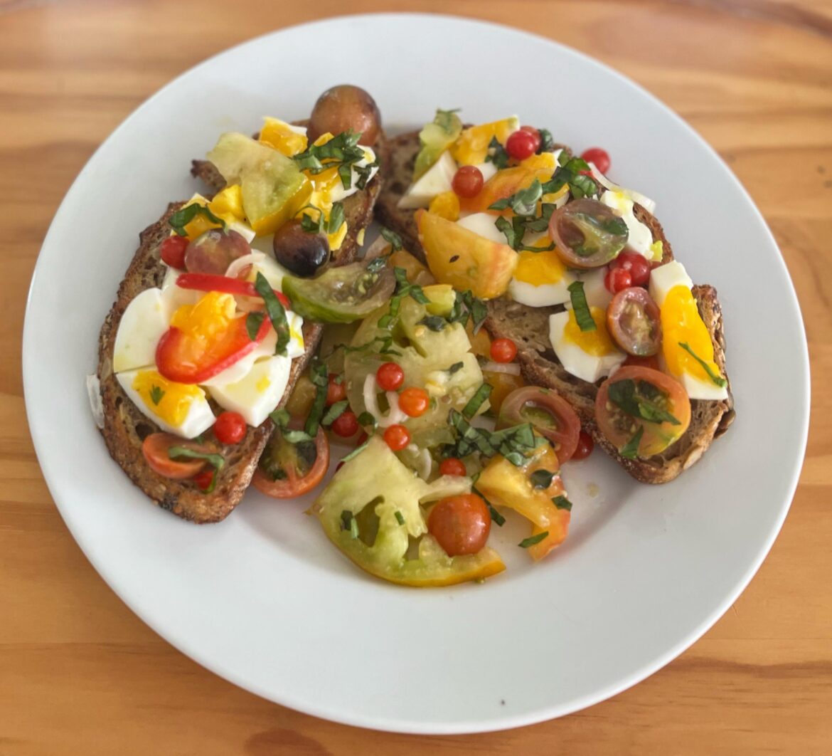 Soft-cooked eggs over super seeded sourdough toast with a white balsamic tomato/basil salad