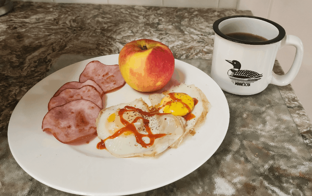 Eggs with hot sauce, canadian bacon, an apple and a cup of coffee :)
