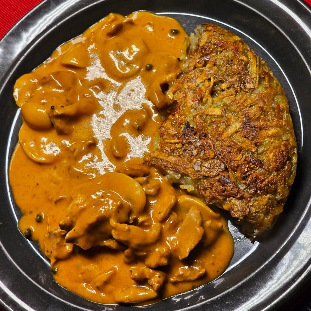 Rösti and sliced pork at a mushroom cream sauce Madagascar style (with green peppercorns)