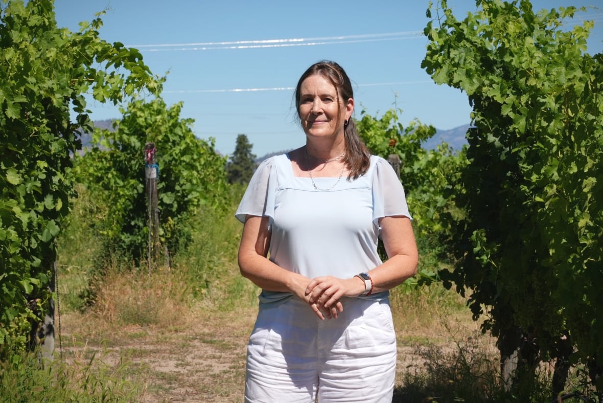 Séverine Pinte , a caucasian woman, stands in front of grape vines on a sunny day.