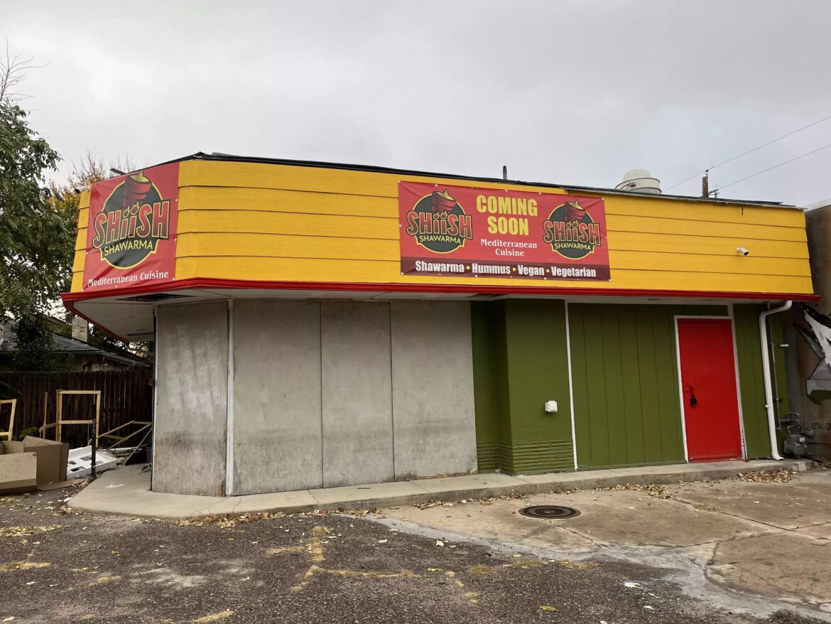 a green and yellow building with a "coming soon" sign hanging on it
