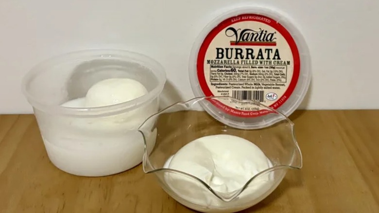 an open container of Vantia burrata with one ball in a glass bowl
