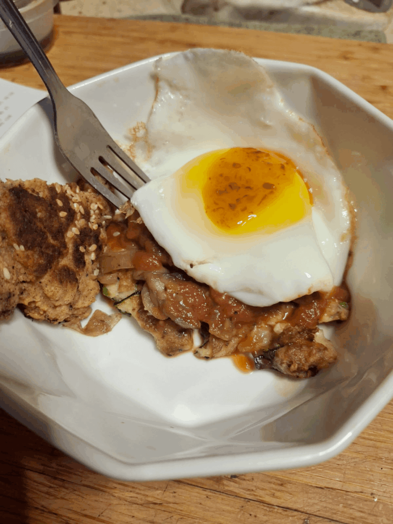 Breakfast: A Love Story. from bottom up: Zucchini pancake, topped with sauteed onions/mushrooms, tomato sauce and a barely set sunny side up egg, hot sauce on top of that. Heaven. 2nd pic NSFW