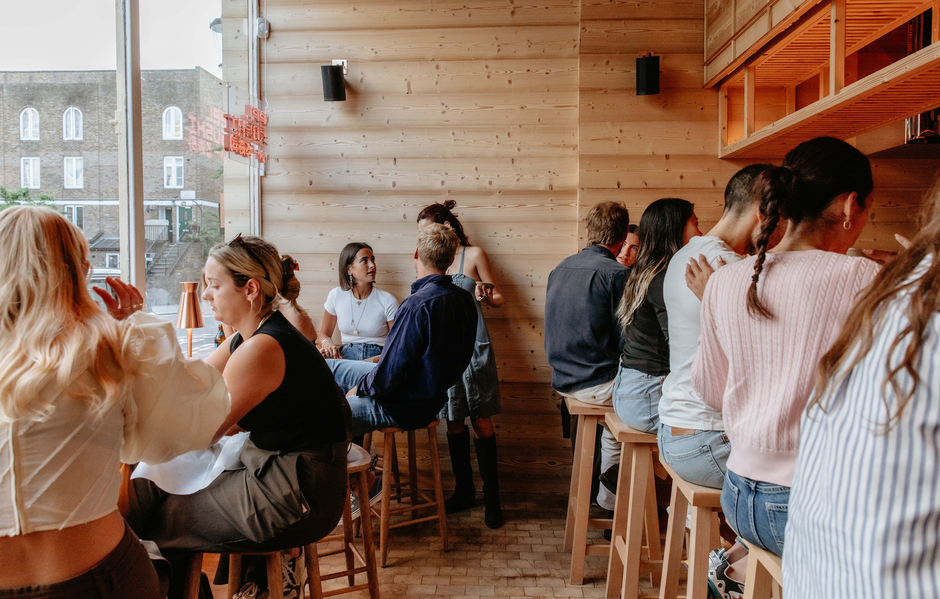 People sitting at a bar with wooden walls.