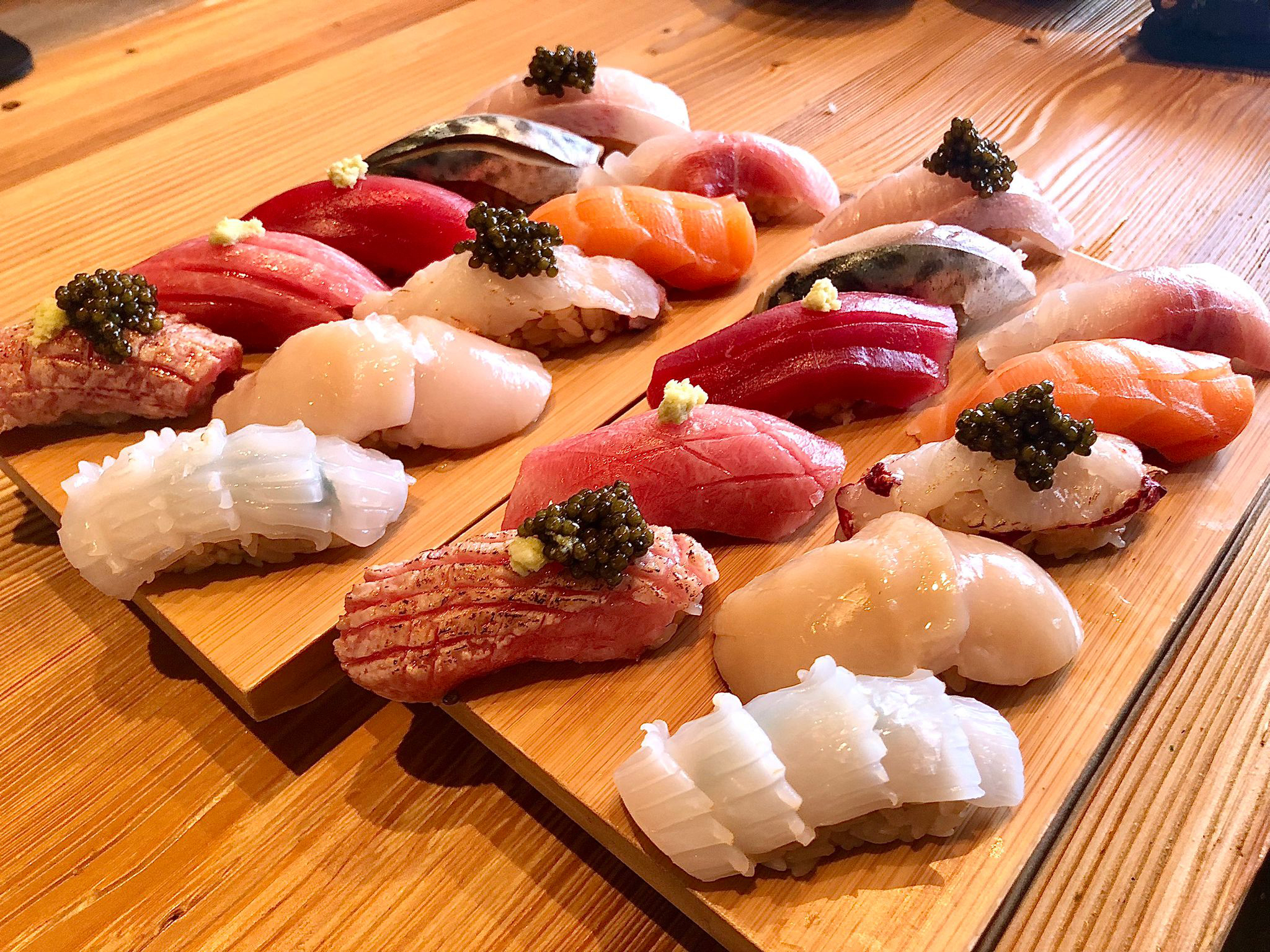 A variety of nigiri sushi on a wooden board.